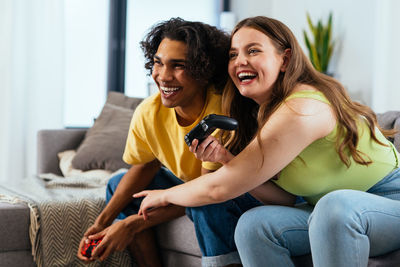 Portrait of smiling friends sitting on sofa at home