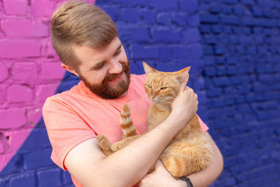 Portrait of smiling young woman with cat with eyes closed