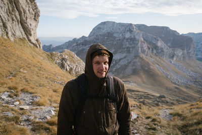 Portrait of young man standing on landscape against mountains