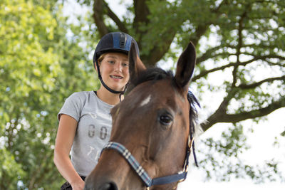 Low angle view of happy teenager riding horse