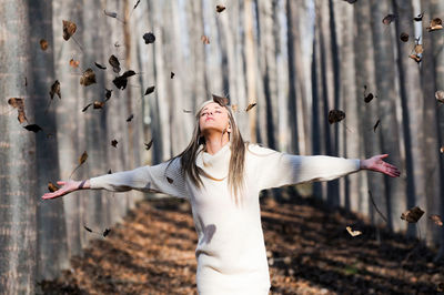 Woman with arms raised standing against wall