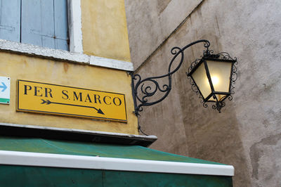 Low angle view of illuminated text on yellow wall