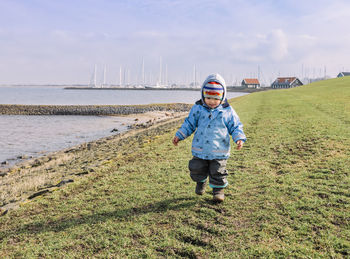 Full length of girl walking on field against sky