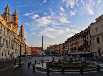 Sculptures in fountain amidst buildings against sky at piazza navona