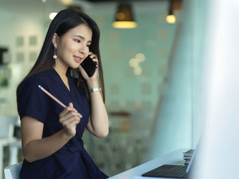 Smiling businesswoman talking on phone at office