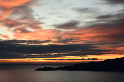 Scenic view of sea against dramatic sky during sunset