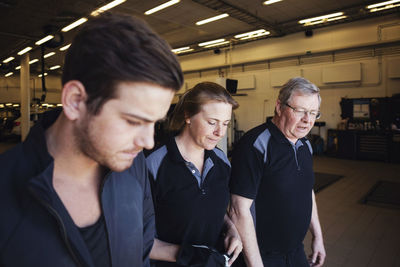 Experts discussing while walking in auto repair shop