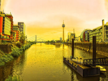 Bridge over river against buildings during sunset