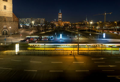 Light trails on road by illuminated buildings in city at night