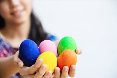 Midsection of girl holding easter eggs against white background