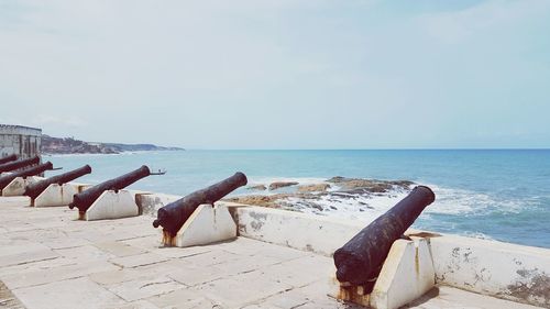 Driftwood on beach by sea against sky