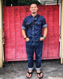 Portrait of smiling man standing against red wall