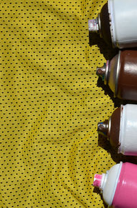 Directly above shot of aerosol cans on yellow textile