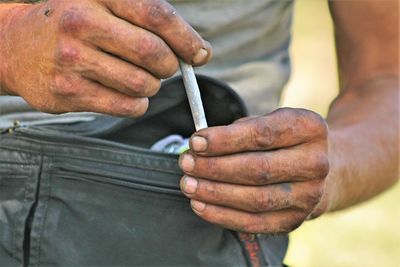 Midsection of man holding marijuana joint