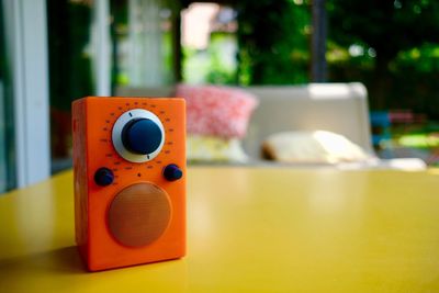 Close-up of orange radio on yellow table