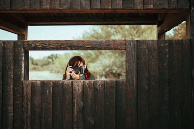 Portrait of woman in sunglasses on wooden fence