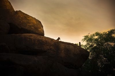 Silhouette rocks on cliff against sky during sunset