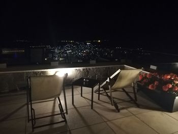 Empty chairs and tables in illuminated building at night