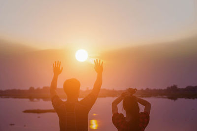 People in front of sea against sky during sunset