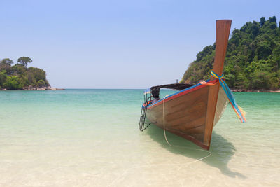 Boat moored on beach against clear sky