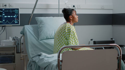 Side view of woman sitting in hospital