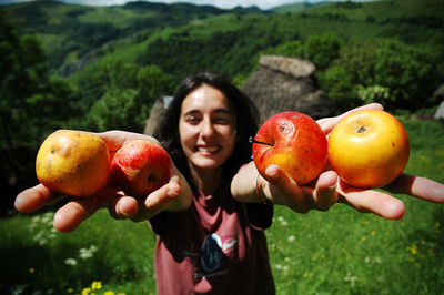 Smiling woman holding apples on mountain