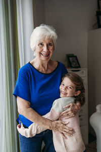 Happy girl embracing grandmother at home
