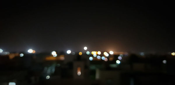 Defocused image of illuminated city against sky at night