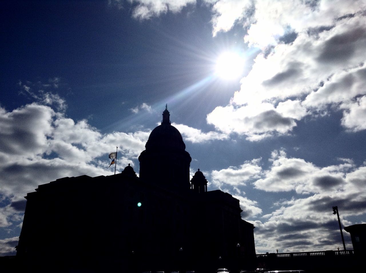 building exterior, architecture, built structure, silhouette, sky, low angle view, religion, place of worship, spirituality, church, sun, cloud - sky, sunbeam, sunlight, cloud, sunset, cathedral, city