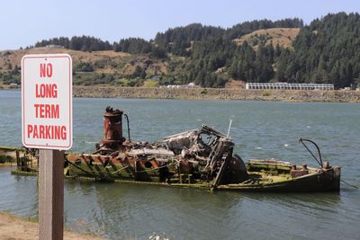 Information sign by lake against sky