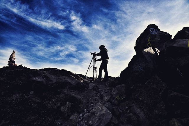 lifestyles, leisure activity, full length, men, sky, rock - object, adventure, cloud - sky, rock formation, hiking, low angle view, standing, nature, casual clothing, vacations, rear view, cliff