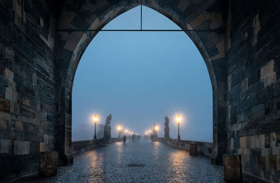 Illuminated walkway against sky at dusk