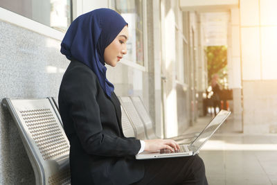 Side view of young woman using mobile phone