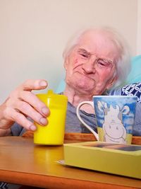 Portrait of man holding drink sitting at table