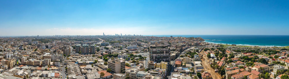 Aerial view of city by sea against clear sky