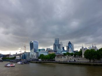 View of buildings by river against cloudy sky