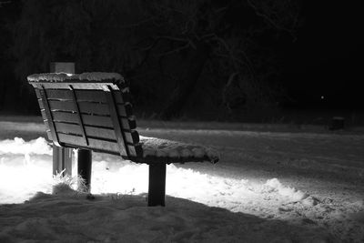 Empty bench on snow covered field