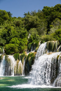 Scenic view of waterfall in forest against clear sky