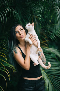 Woman holding cat standing outdoors