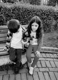 High angle view of siblings sitting on bench at park