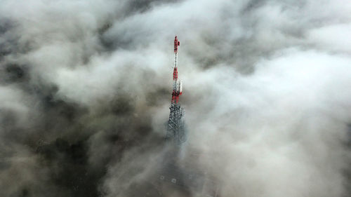 Aerial view of communications tower amidst cloudy sky