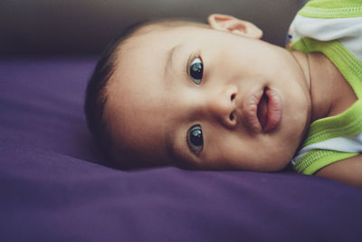 Portrait of cute baby lying on bed at home