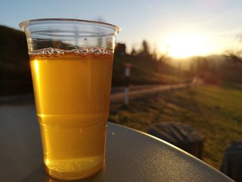 Close-up of beer glass on table against sky during sunset