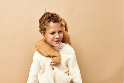 Cute sibling embracing against beige background