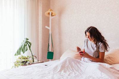 Woman sitting on bed at home