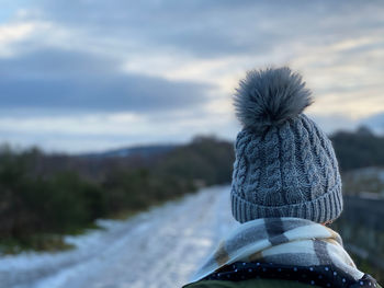 Rear view of woman wearing hat against sky during winter