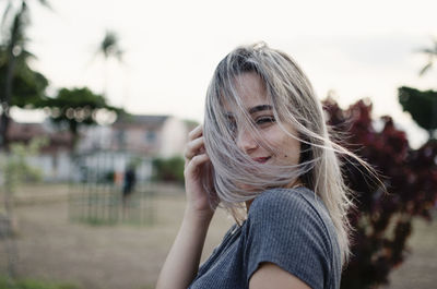 Smiling young woman with blond hair in park