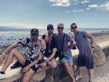 Portrait of friends on beach against sky