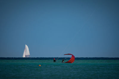 Sailboat in sea against clear blue sky