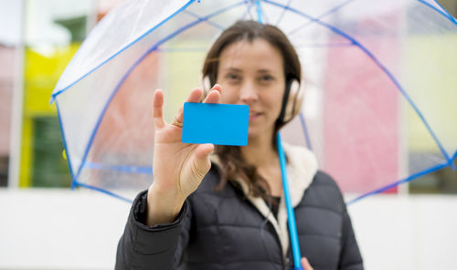 Woman showing business card while holding umbrella